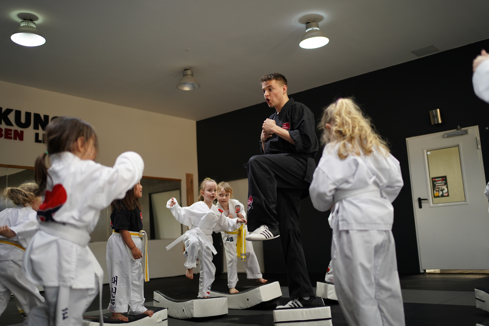 Lehrer zeigt Kindern im Dojo eine Kampfkunst-Technik